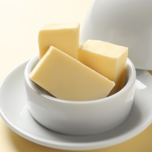 A nice ceramic butter dish filled with sticks of yellow butter sitting on a nice countertop.