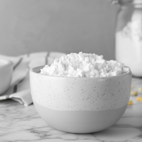 A nice ceramic bowl filled with cornstarch sitting on a nice marble countertop.