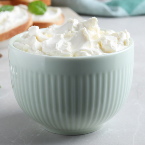 A ceramic blue bowl filled with fluffy cream cheese sitting on a nice clean countertop.