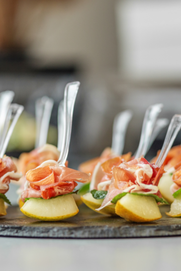 A serving tray filled with beautiful appetizers with serving forks, ready to be eaten.