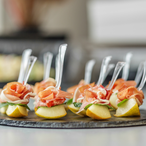 A serving tray filled with beautiful appetizers with serving forks, ready to be eaten.