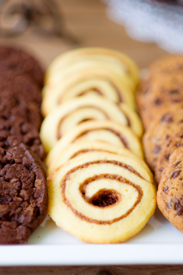 A beautifully styled cookie platter with 3 different types of cookies resting on a nice party table.