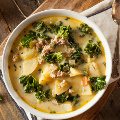 A warm bowl of Zupa Toscana soup on a nice rustic wooden table.