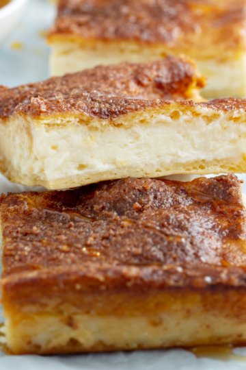 Cheese cake bars resting on a parchment paper serving area.