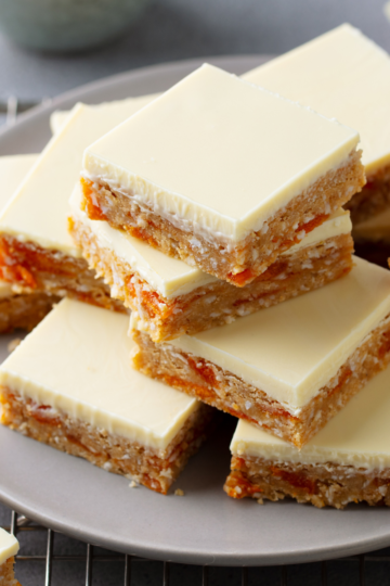 A nice plate filled with cookie bars that are nicely iced with a white frosting.