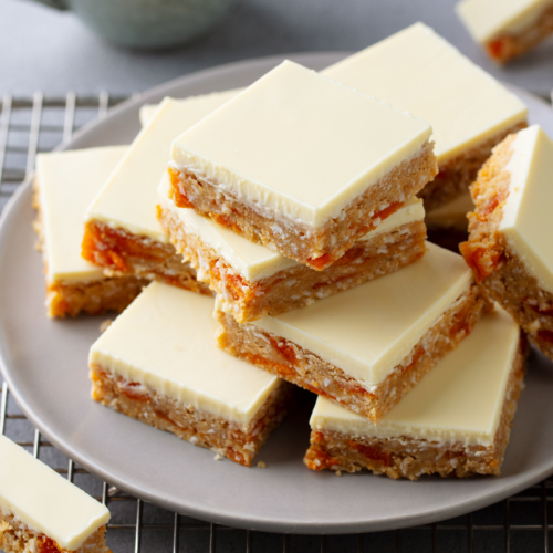 A nice plate filled with cookie bars that are nicely iced with a white frosting.