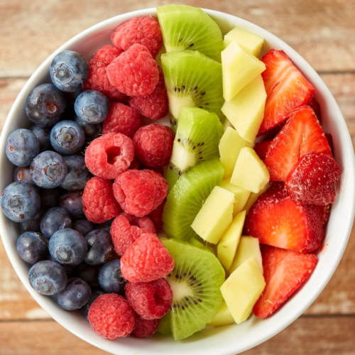 Colorful fruit bowl with strawberries, blueberries, kiwi and pineapple arranged neatly for a party serving table.