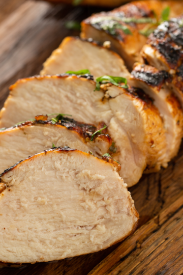 A nicely cooked barbecue chicken, cut and displayed on a wooden cutting board.
