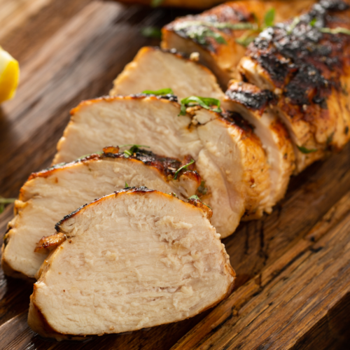 A nicely cooked barbecue chicken, cut and displayed on a wooden cutting board.