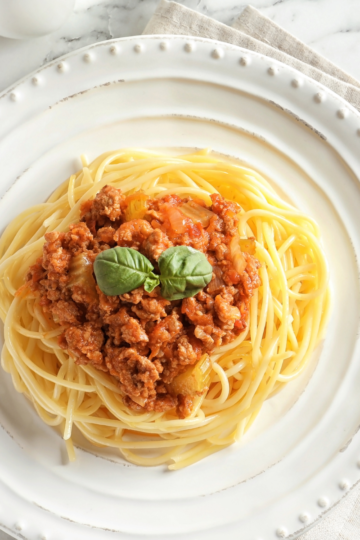 Spaghetti on a beautiful white plate served with a nice meat sauce.