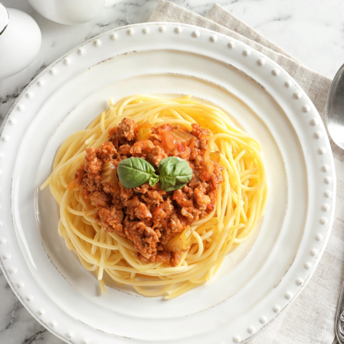 Spaghetti on a beautiful white plate served with a nice meat sauce.