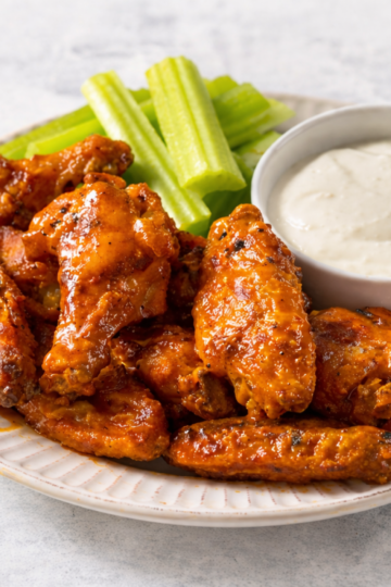 Buffalo chicken wings served with celery sticks and ranch dressing, used to illustrate a wings per person calculator for parties and large groups.