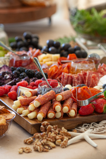Elaborate charcuterie and appetizer spread for a graduation party with meats, cheeses, fruits, crackers and nuts on wooden boards.