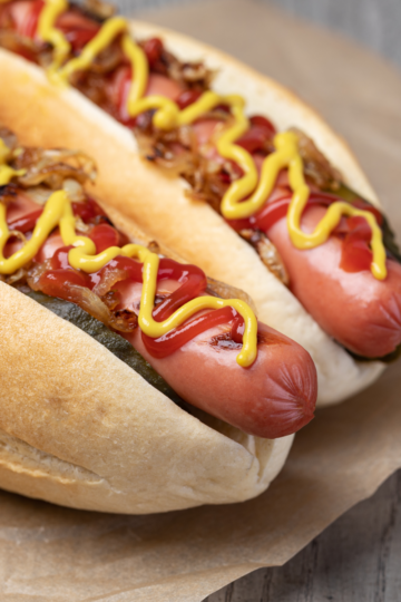 Perfectly cooked hotdogs in buns topped with mustard and ketchup ready to be eaten.