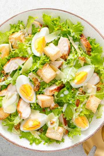 Large bowl of fresh green salad for a crowd with eggs, croutons and chicken.