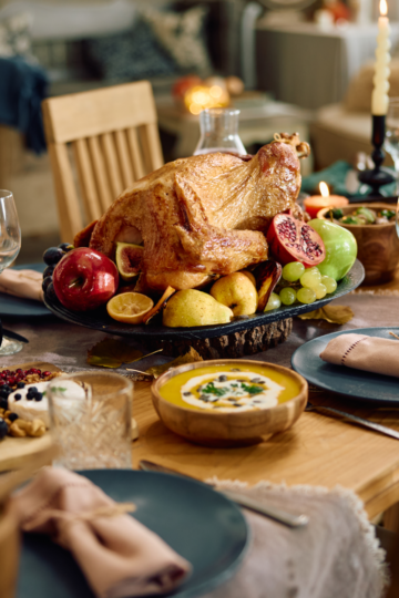 A perfectly set up thanksgiving table set with turkey and fancy table settings. Ready with the perfect amount of food.
