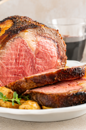 Sliced bone-in prime rib roast showing medium-rare interior, illustrating how much prime rib per person to buy