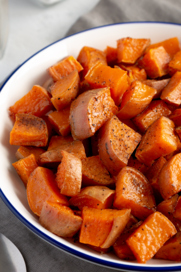 Bowl of roasted sweet potato cubes seasoned with salt and pepper, served as a side dish.