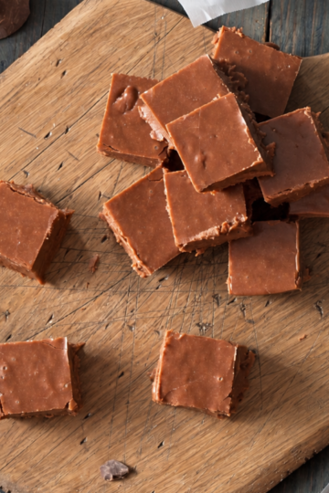 Cubes of rich chocolate fudge sitting on a rustic cutting board.